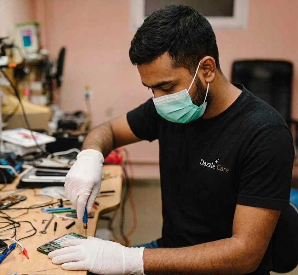 DazzleCare technician repairing a phone logic board at the service bench